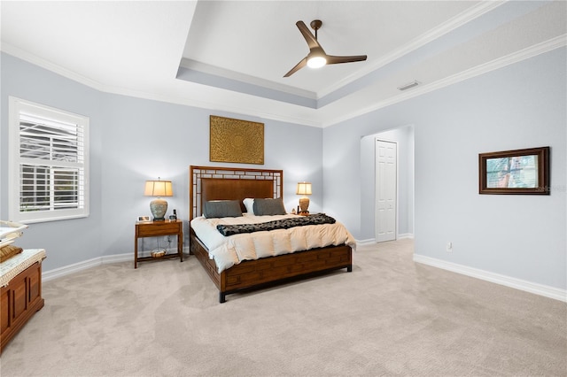 carpeted bedroom with a raised ceiling, a closet, ceiling fan, and crown molding