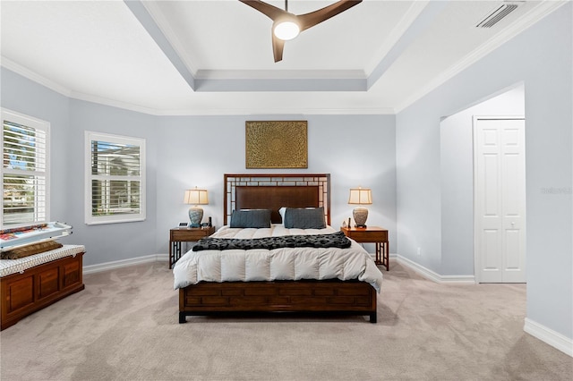 bedroom with light colored carpet, ceiling fan, crown molding, and a tray ceiling