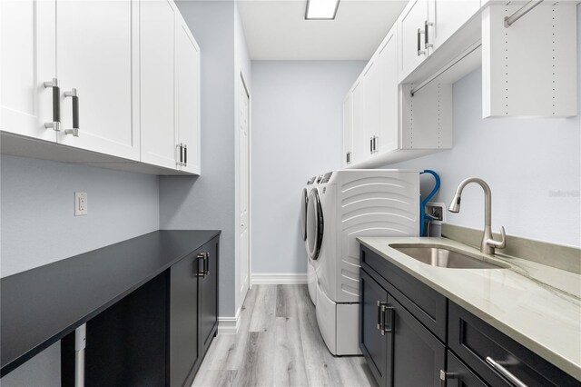 laundry area featuring washer and clothes dryer, cabinets, sink, and light hardwood / wood-style floors