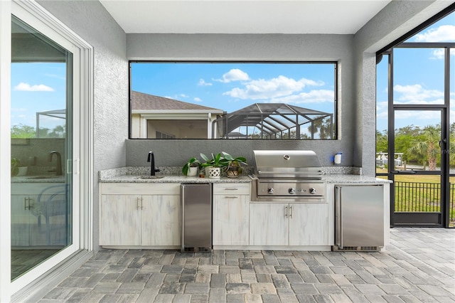 kitchen with light stone countertops, sink, and stainless steel refrigerator