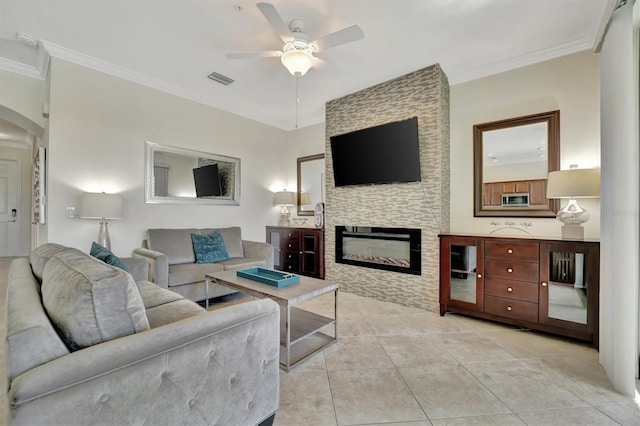 tiled living room featuring a fireplace, ceiling fan, and crown molding