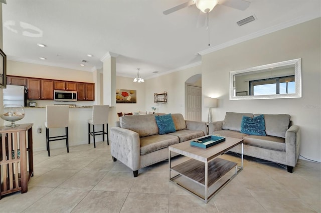 tiled living room with ceiling fan with notable chandelier and ornamental molding