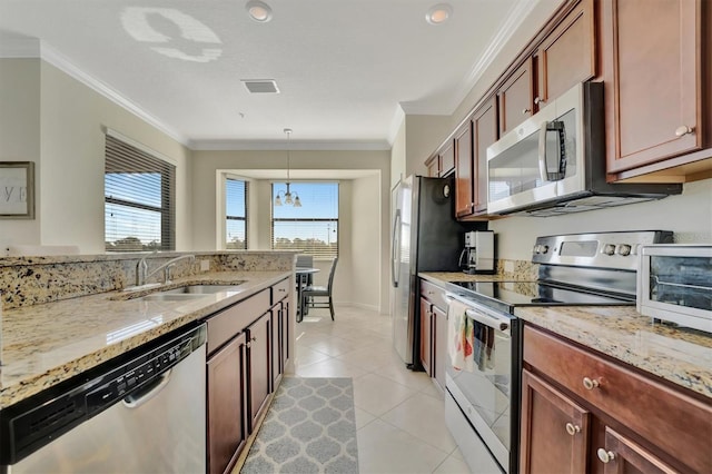 kitchen featuring crown molding, hanging light fixtures, light tile patterned floors, light stone countertops, and appliances with stainless steel finishes