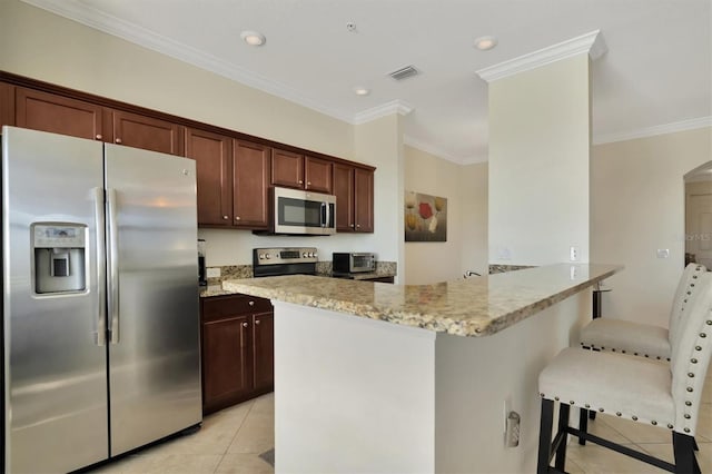 kitchen featuring light stone counters, crown molding, a breakfast bar area, light tile patterned flooring, and appliances with stainless steel finishes