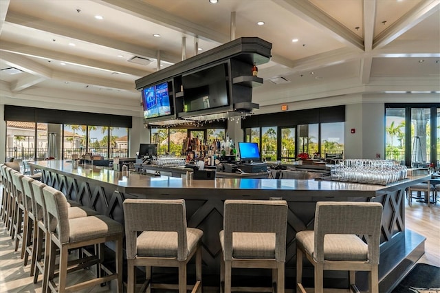 bar with beam ceiling, light hardwood / wood-style floors, and a wealth of natural light