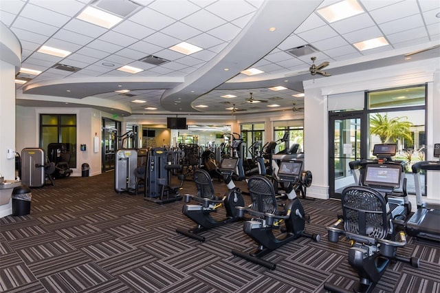 gym featuring dark colored carpet, a paneled ceiling, and ceiling fan