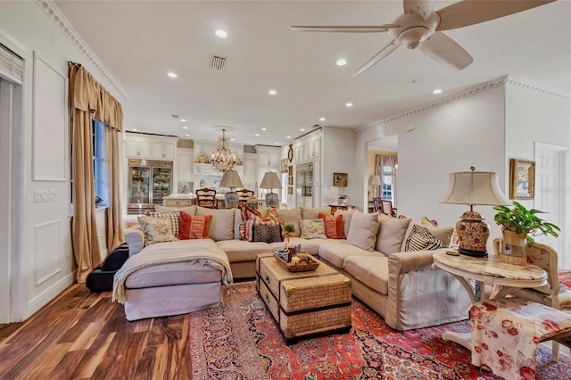 living room with hardwood / wood-style flooring, ceiling fan with notable chandelier, and crown molding