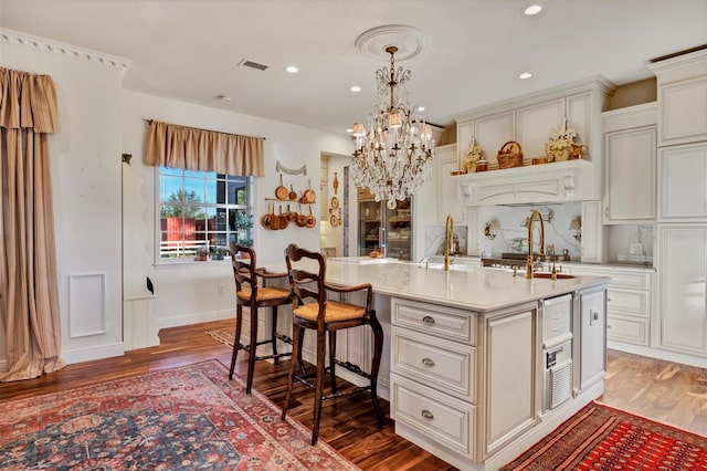 kitchen with pendant lighting, dark hardwood / wood-style flooring, and a center island with sink