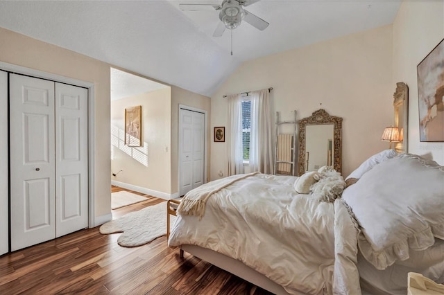 bedroom featuring hardwood / wood-style flooring, ceiling fan, vaulted ceiling, and two closets