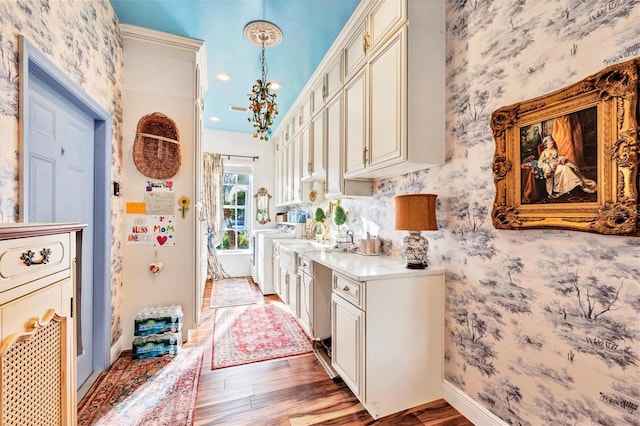 kitchen with cream cabinets, washer / clothes dryer, light hardwood / wood-style flooring, and hanging light fixtures