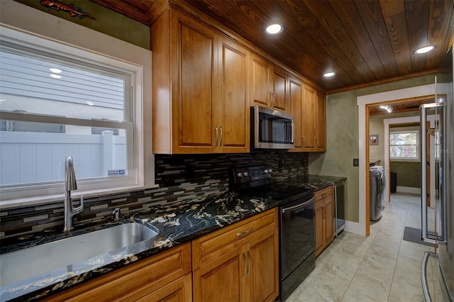 kitchen featuring decorative backsplash, black range with electric cooktop, dark stone counters, and sink