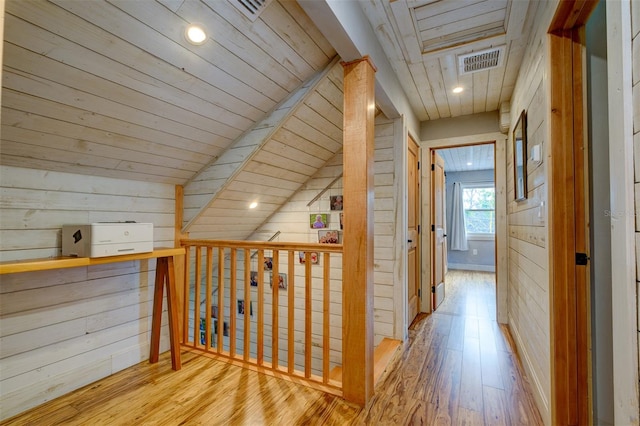 corridor featuring light hardwood / wood-style floors, vaulted ceiling, wooden walls, and wood ceiling