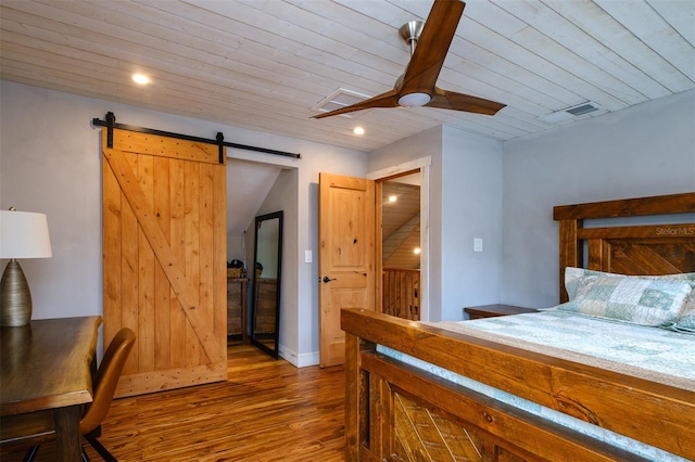 bedroom featuring hardwood / wood-style floors, ceiling fan, a barn door, and wooden ceiling