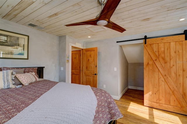 bedroom featuring light wood-type flooring, wood ceiling, vaulted ceiling, ceiling fan, and a barn door