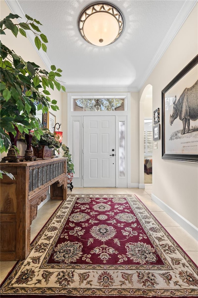 tiled foyer featuring a textured ceiling and crown molding