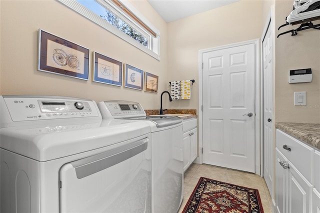 clothes washing area with washer and clothes dryer, sink, light tile patterned floors, and cabinets