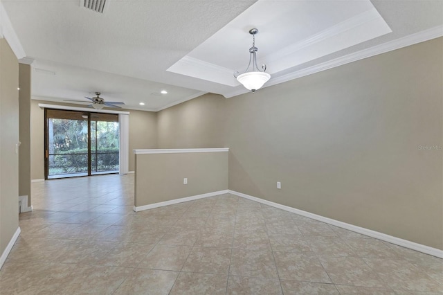 empty room featuring a textured ceiling, a raised ceiling, ceiling fan, crown molding, and light tile patterned flooring