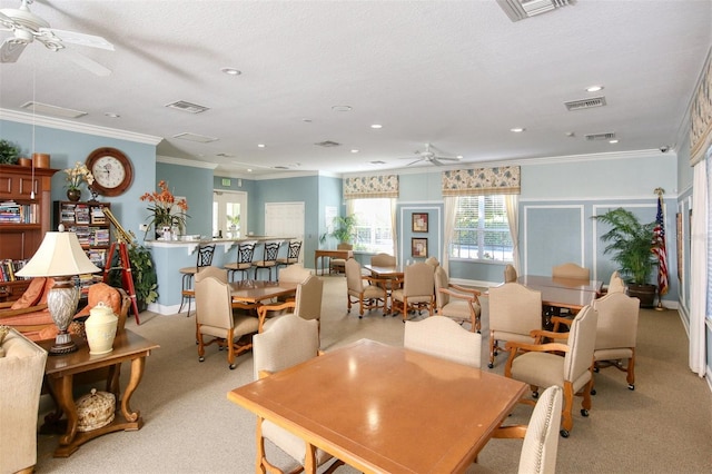 dining room with crown molding, ceiling fan, light colored carpet, and a textured ceiling