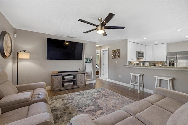 living room with dark hardwood / wood-style floors, ceiling fan, and sink