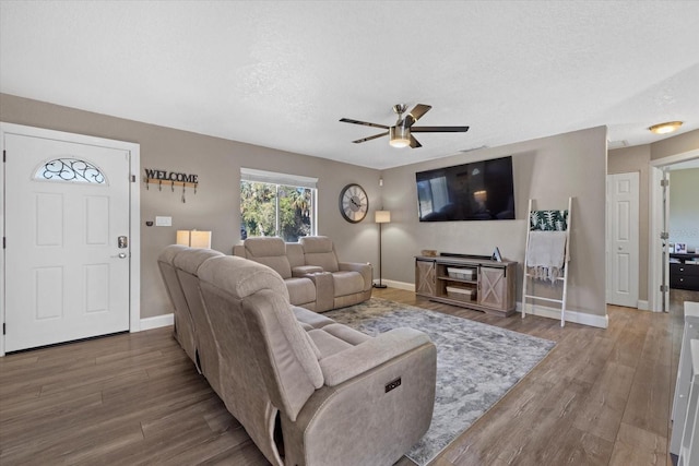 living room with hardwood / wood-style flooring, ceiling fan, and a textured ceiling