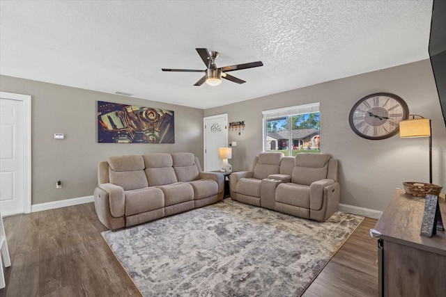 living room featuring a textured ceiling, ceiling fan, and dark wood-type flooring