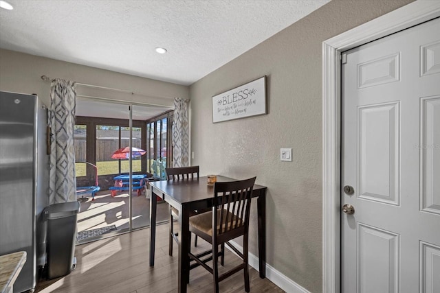 dining space with a textured ceiling and hardwood / wood-style flooring