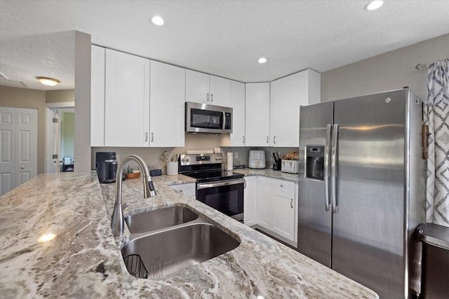 kitchen featuring white cabinets, sink, a textured ceiling, light stone counters, and stainless steel appliances