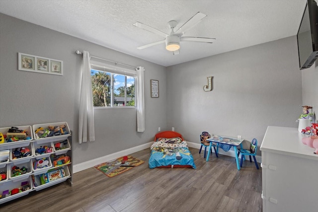 game room with ceiling fan, hardwood / wood-style floors, and a textured ceiling