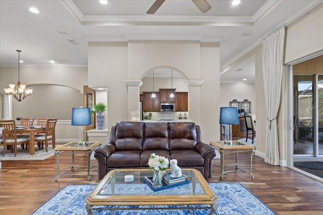 living room featuring ceiling fan with notable chandelier, dark hardwood / wood-style flooring, and ornamental molding