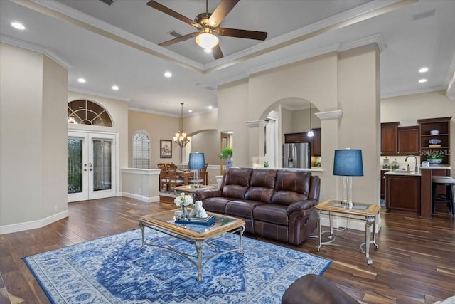 living room with crown molding, dark hardwood / wood-style flooring, ceiling fan with notable chandelier, and french doors