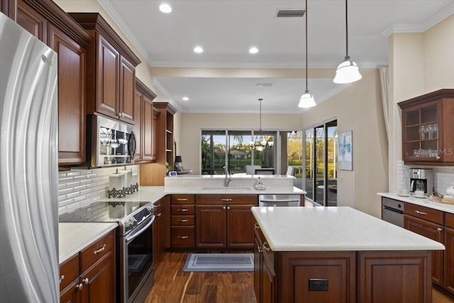 kitchen featuring sink, stainless steel appliances, tasteful backsplash, kitchen peninsula, and pendant lighting