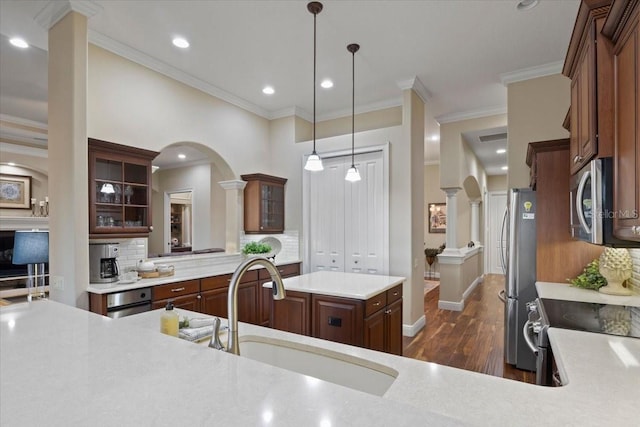 kitchen featuring appliances with stainless steel finishes, dark hardwood / wood-style flooring, sink, pendant lighting, and a center island