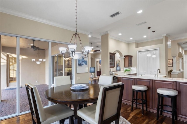 dining room featuring sink, ceiling fan with notable chandelier, crown molding, and dark wood-type flooring