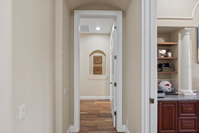 corridor featuring dark hardwood / wood-style flooring and ornate columns