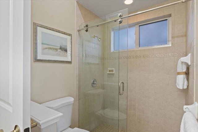 bathroom featuring a shower with shower door and toilet