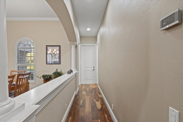 hallway with decorative columns, dark wood-type flooring, and ornamental molding