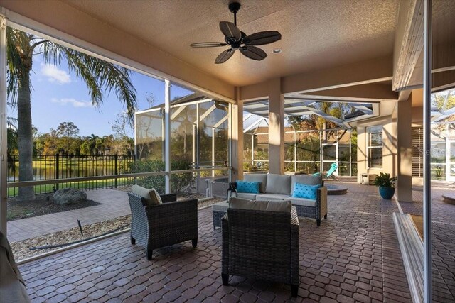 sunroom with ceiling fan and a water view