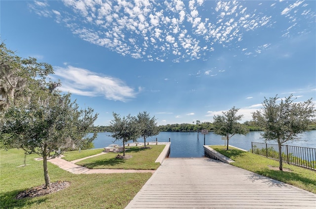 view of dock with a yard and a water view