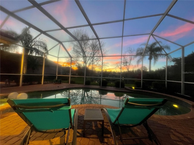 pool at dusk with a lanai and a patio area