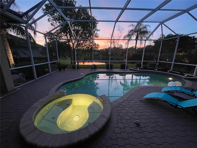 pool at dusk with glass enclosure and an in ground hot tub