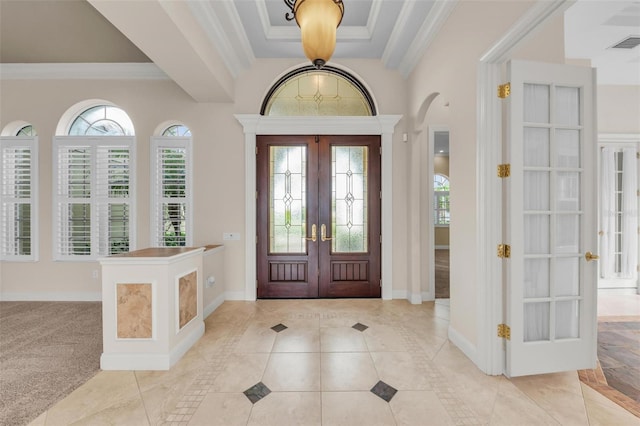 entrance foyer with light colored carpet, ornamental molding, and french doors