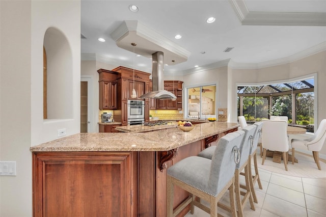 kitchen with kitchen peninsula, island range hood, crown molding, hanging light fixtures, and light tile patterned flooring