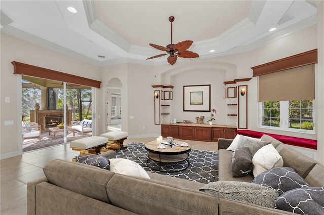 living room with a tray ceiling, crown molding, ceiling fan, and light tile patterned flooring