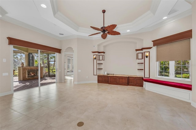 unfurnished living room featuring a healthy amount of sunlight, a raised ceiling, and crown molding