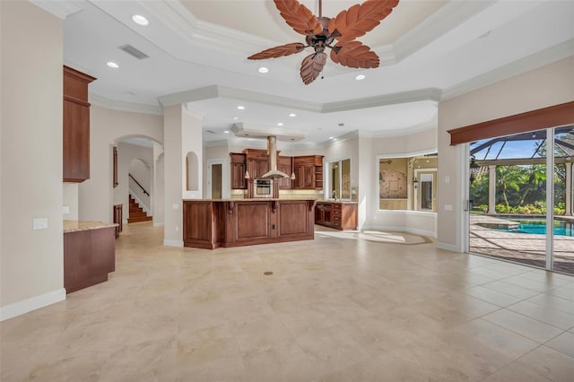 kitchen with a tray ceiling, ceiling fan, crown molding, and island range hood