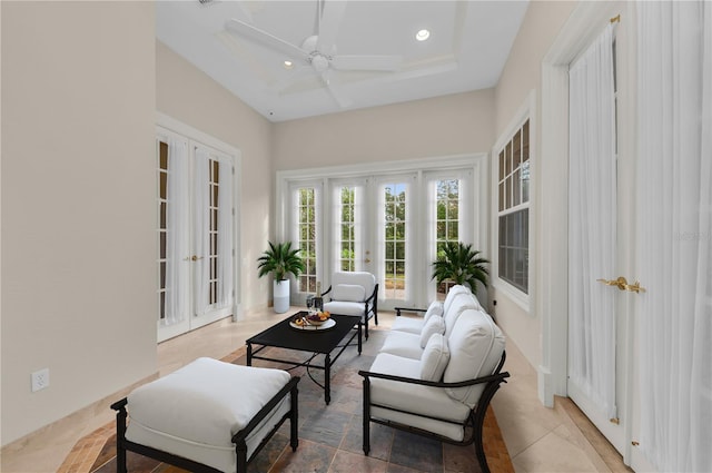 sunroom with a raised ceiling, ceiling fan, and french doors