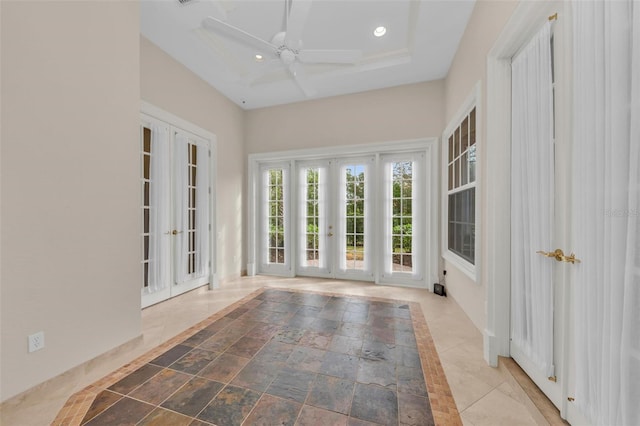 unfurnished sunroom featuring ceiling fan, a tray ceiling, and french doors