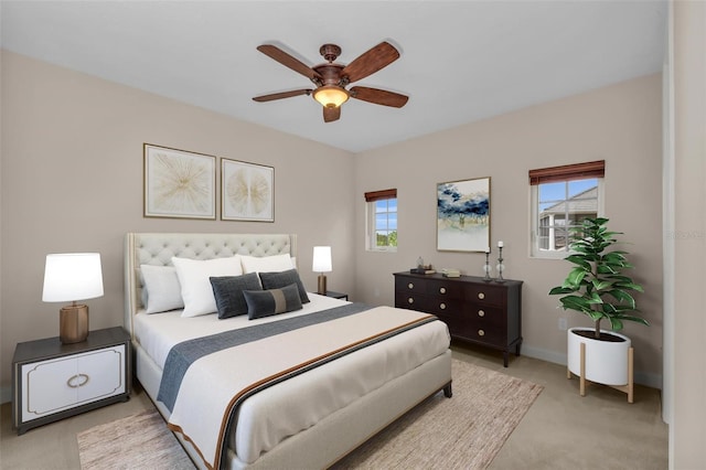 bedroom with ceiling fan, light carpet, and multiple windows