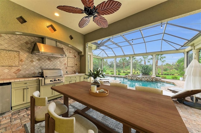 view of patio with glass enclosure, a pool with hot tub, ceiling fan, a grill, and exterior kitchen