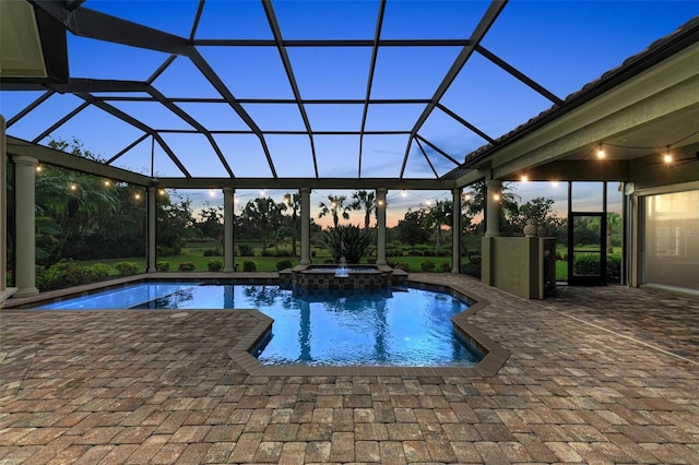 pool at dusk with an in ground hot tub, a patio, and glass enclosure